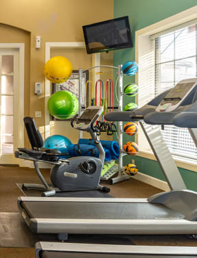 a spacious fitness room with cardio equipment and weights