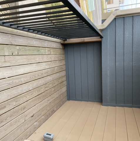 A sunroom with a wooden wall and a black metal grate.