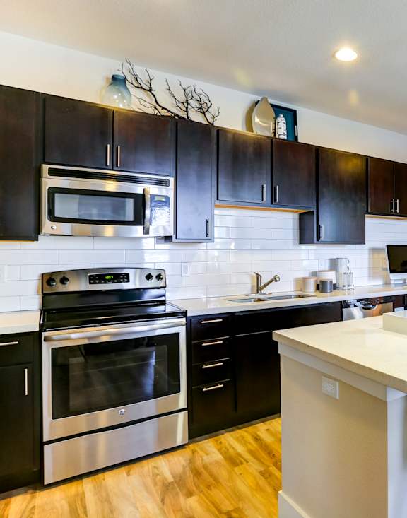 A modern kitchen with a white island and black cabinets.