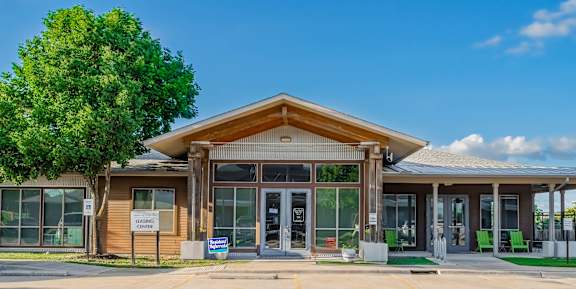 the front of a building with glass doors and a tree