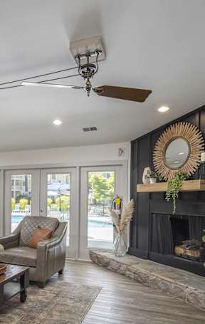 A living room with a grey couch, a wooden coffee table, and a fireplace with a mirror above it.