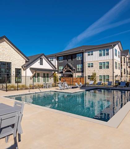A pool with a table and chairs in front of a building.