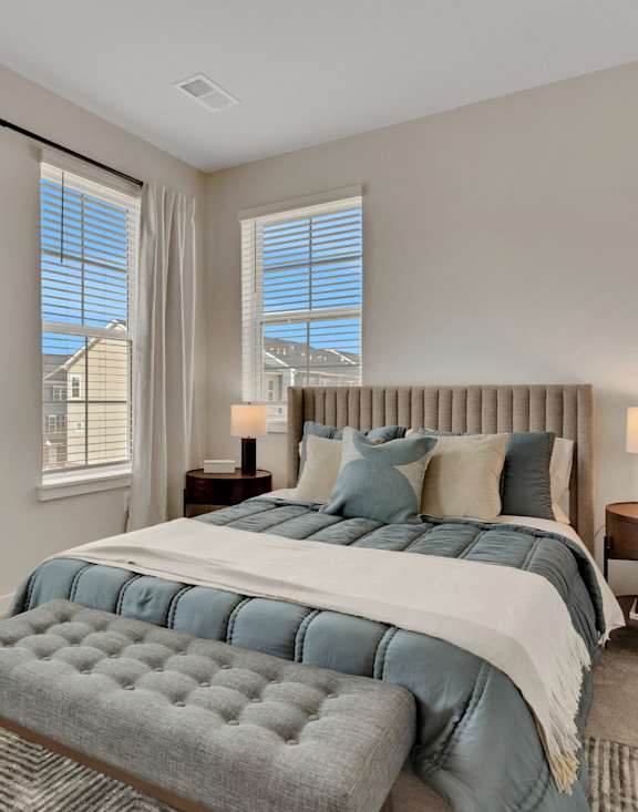 a bedroom with a large bed and two windows