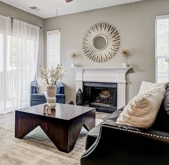 A living room with a fireplace, a ceiling fan, and a large mirror on the wall.