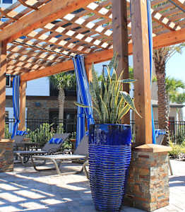 A wooden pergola with blue vases and plants underneath it.
