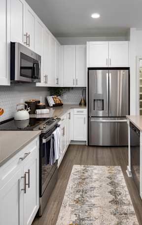 A modern kitchen with white cabinets and a tiled backsplash.