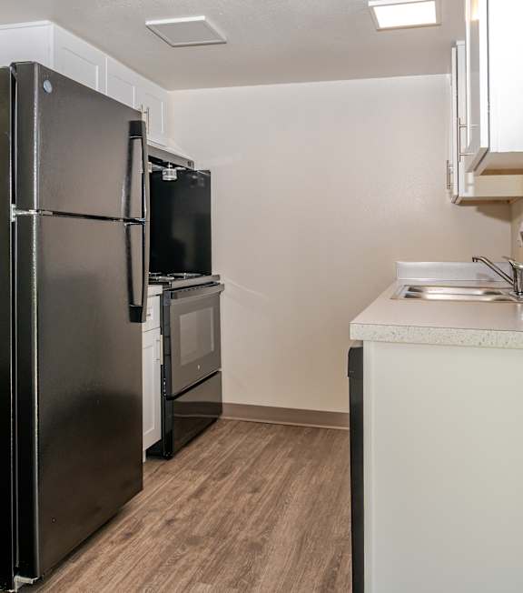 A kitchen with white cabinets and a black dishwasher.