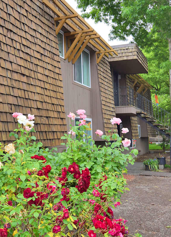 the outside of a cabin with flowers in front of it