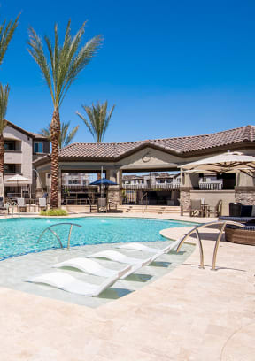 a swimming pool with chaise lounge chairs and umbrellas in front of a hotel