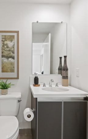 a small bathroom with a toilet sink and mirror at The Fairfax Flats Apartments, Los Angeles, CA, 90019