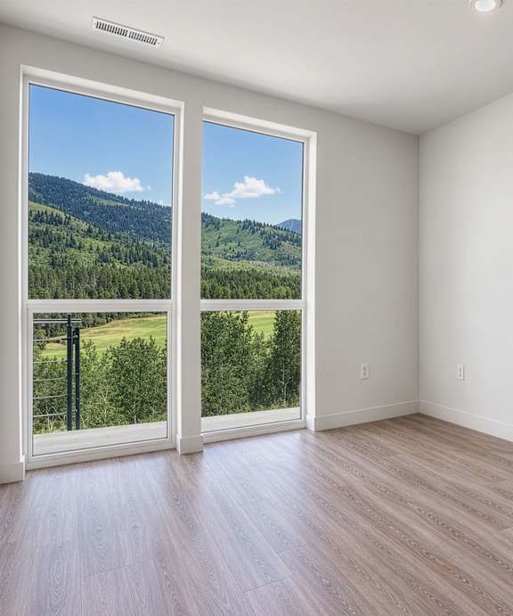 A room with a view of a forest through a sliding glass door.