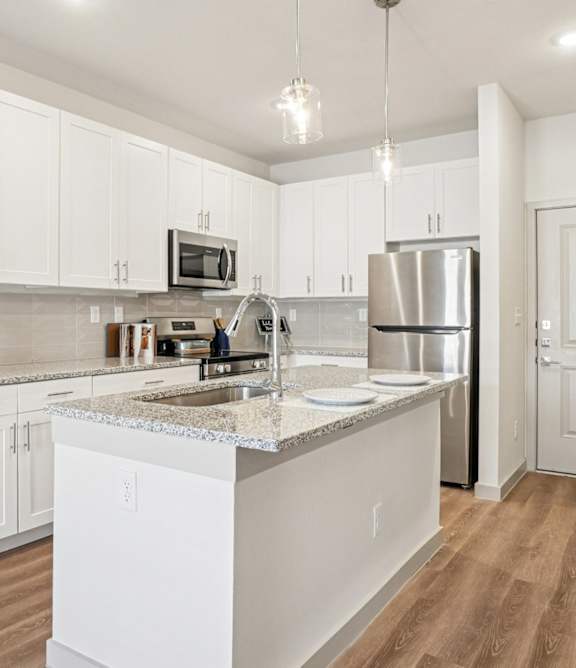 A kitchen with white cabinets and a marble countertop.