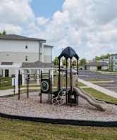 A playground with a green slide and a brown wooden structure.