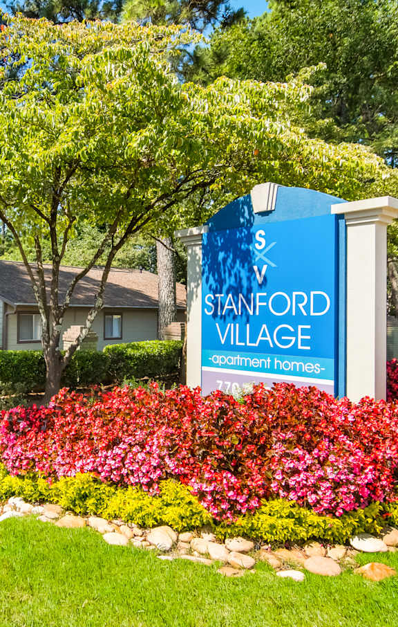 A sign for Stanford Village is in front of a house.