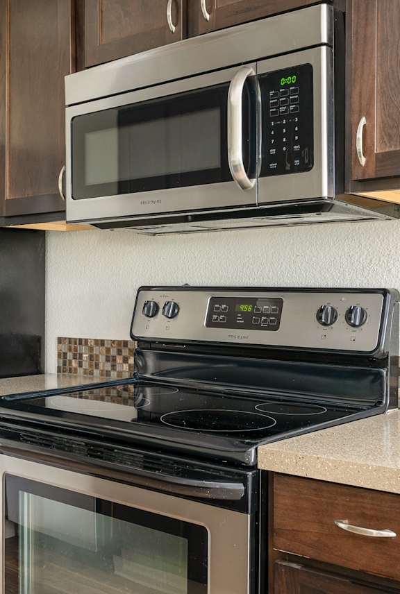 A black refrigerator is next to a black microwave in a kitchen.