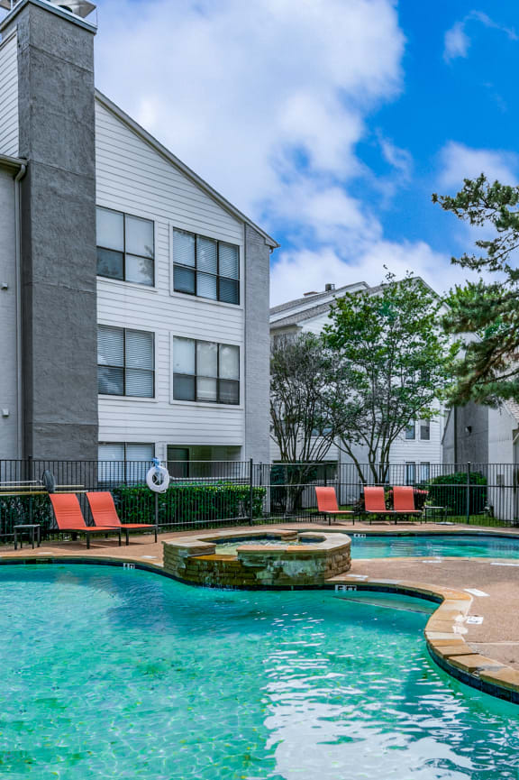 a swimming pool with orange chairs and a building in the background