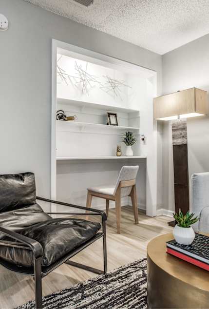 A black leather chair sits in a living room with a white couch and a coffee table.
