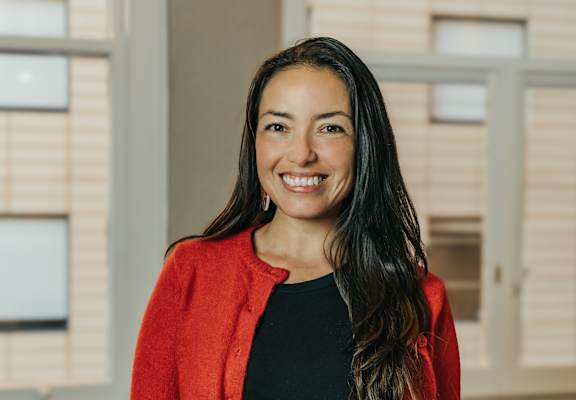 a woman in a red jacket and black shirt is smiling at the camera