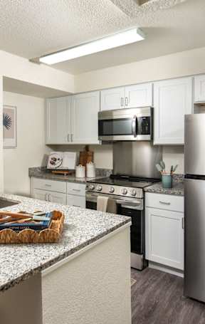A modern kitchen with a stainless steel refrigerator and white cabinets.at The Lucille Apartments, Stuart, FL