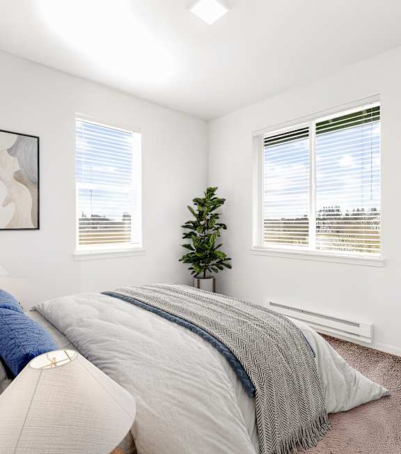 A bedroom with a large bed and a small tree in the corner.