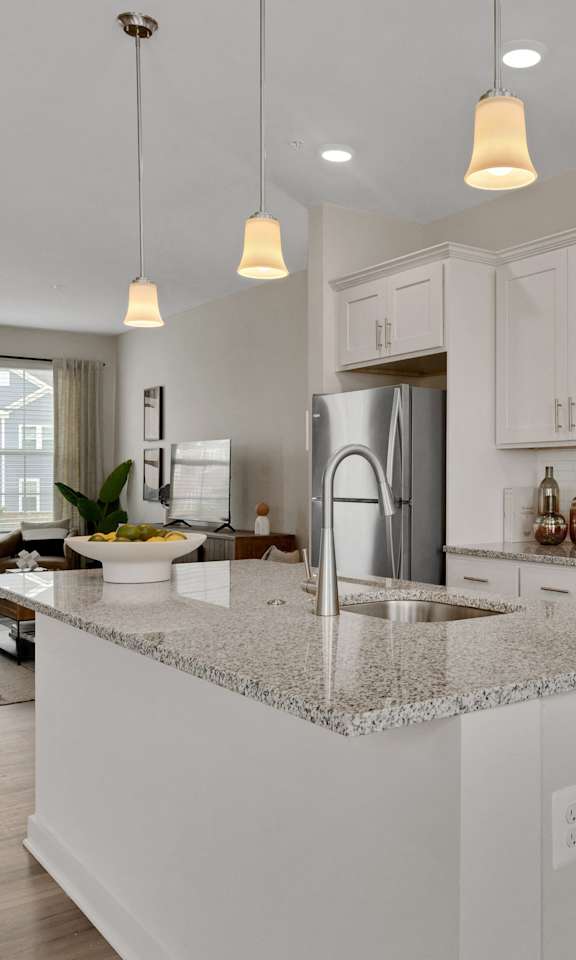 an open kitchen and living room with white cabinets and granite counter tops