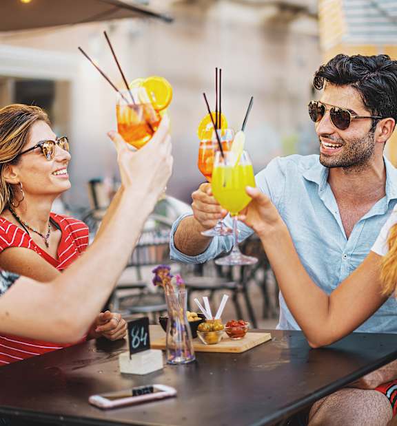 Four people toasting with drinks at a bar.