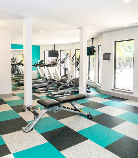 a gym with cardio machines and weights on a checkered floor