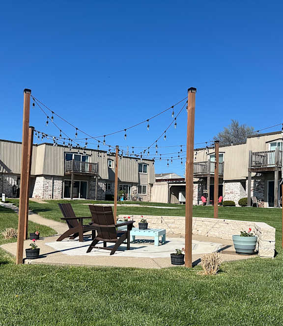 A garden with a fire pit in front of an apartment building, offering a cozy outdoor space.