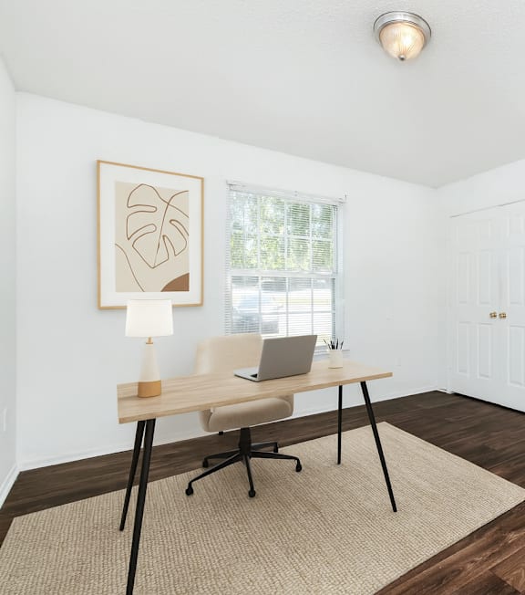 A room with a desk and a chair with a laptop on it.