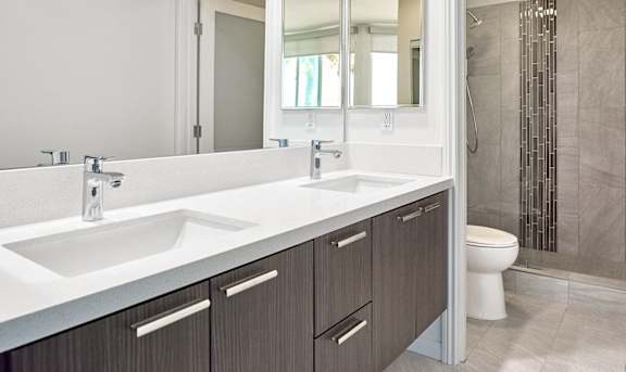 A bathroom with a white sink and brown cabinets at Esprit Apartments, California, 90292.