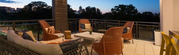 a balcony with a view of a sunset and chairs and a table