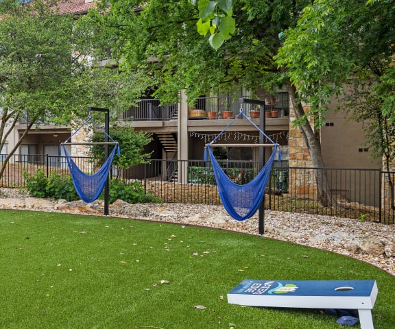 a grassy area with two hammocks and a seesaw