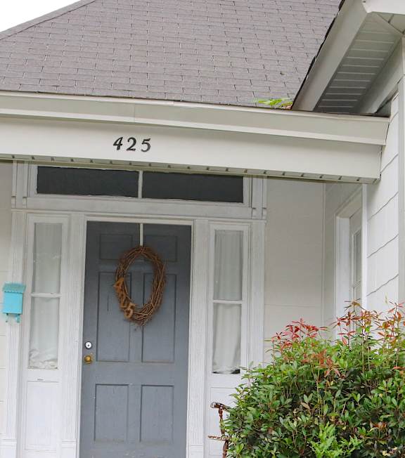 the front of a white house with a blue door