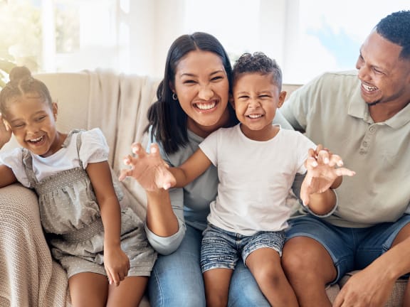a family sitting on a couch smiling and waving to the camera