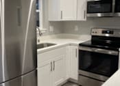 Thumbnail 5 of 19 - A modern kitchen with a stainless steel refrigerator and white cabinets.