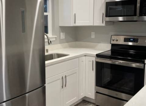 A modern kitchen with a stainless steel refrigerator and white cabinets.