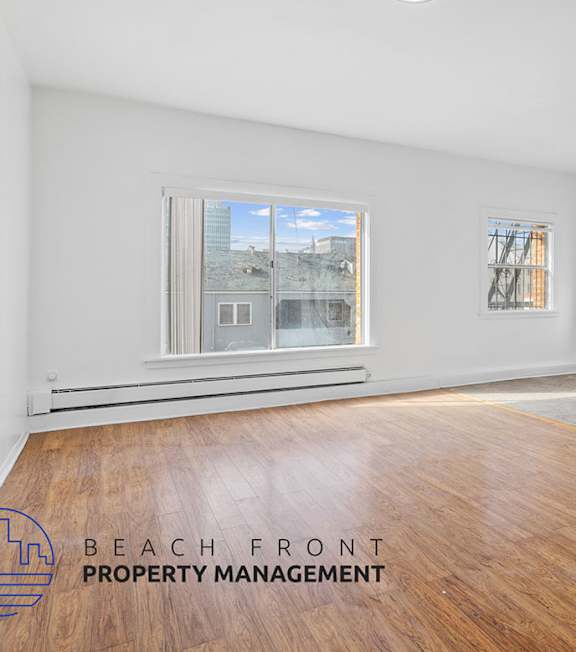 A room with a window overlooking a cityscape and a wooden floor.