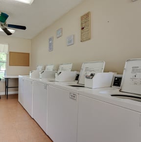 a laundry room with washers and dryers and a table with chairs  at Arbors Of Cleburne, Texas, 76033