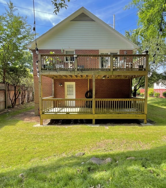 a small brick house with a porch on a grass yard