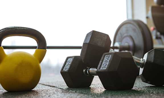 A fitness center image with a kettlebell and dumbbells at Arbours at Covington Apartments, Covington, GA