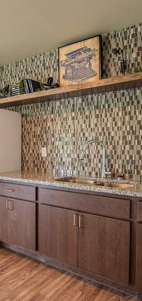 A kitchen with a white refrigerator, brown cabinets, and a black and white checkered backsplash.