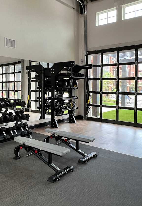 a spacious fitness center with cardio equipment and windows
