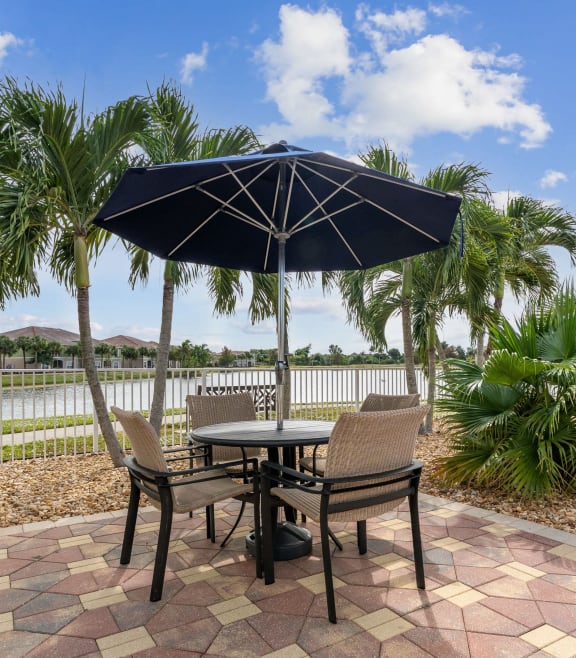 a patio with a table umbrella and chairs next to a pool at Bay Breeze Villas, Fort Myers, Florida