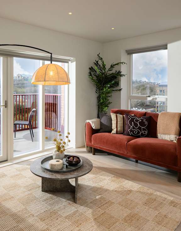 A living room with a green couch, orange chair, and a glass coffee table.