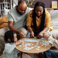 A family is playing a jigsaw puzzle together in their living room.