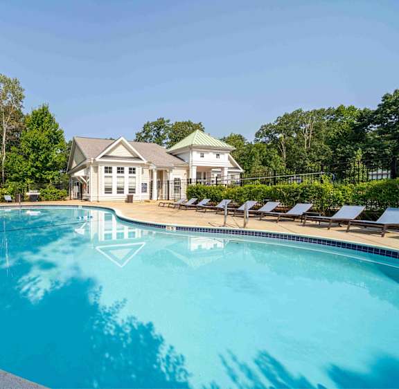 A large swimming pool in front of a house with a green lawn.