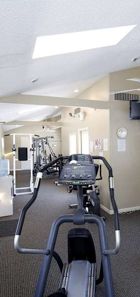 a gym with various machines and a ceiling fan