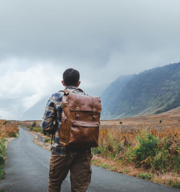 a man with a backpack walking down a road