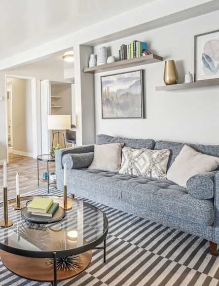 A living room with a grey couch and a glass coffee table.