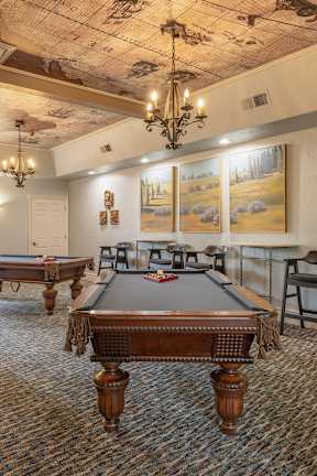 A room with a pool table and a painting of a landscape on the wall.